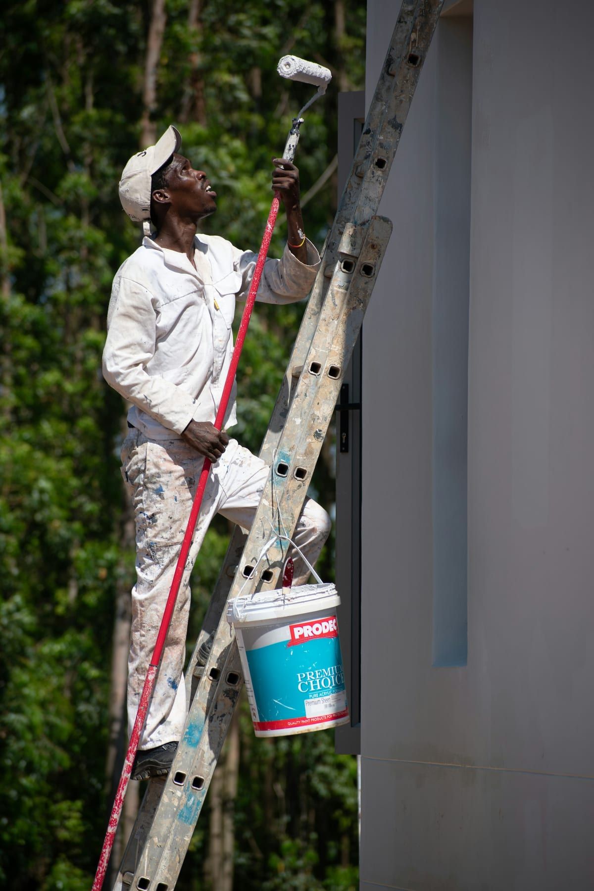 Schilder in witte werkkleding op een ladder schildert een muur